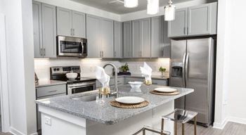 Kitchen with stainless steel appliances, granite counters, and shaker-style cabinets at The Retreat at Fairhope Village in Fairhope, AL